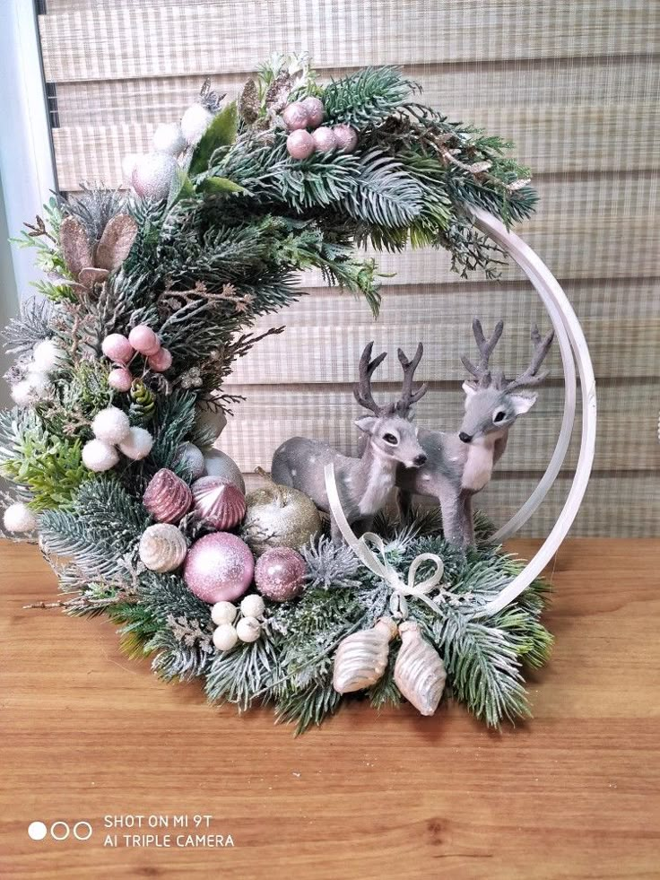 a christmas wreath with two deers and ornaments on it, sitting on a table