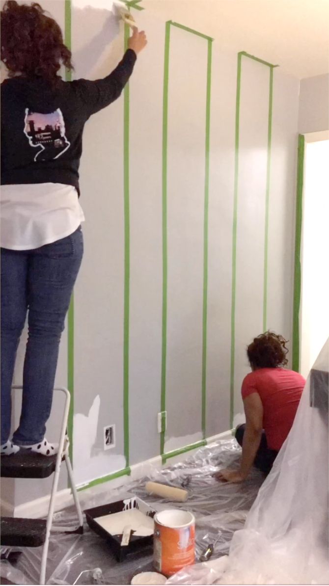 two women are painting the walls in a room that is being remodeled with green tape