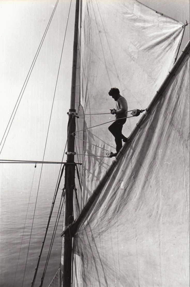 a man standing on the side of a sail boat