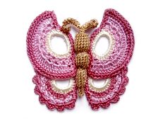 a pink and gold butterfly brooch sitting on top of a white surface