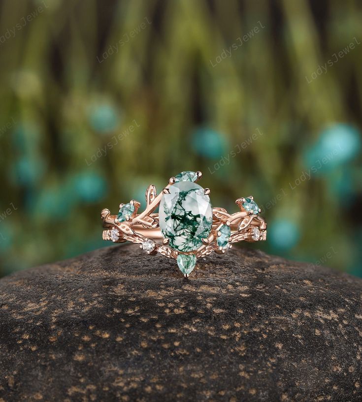 a ring with green and white stones sitting on top of a rock