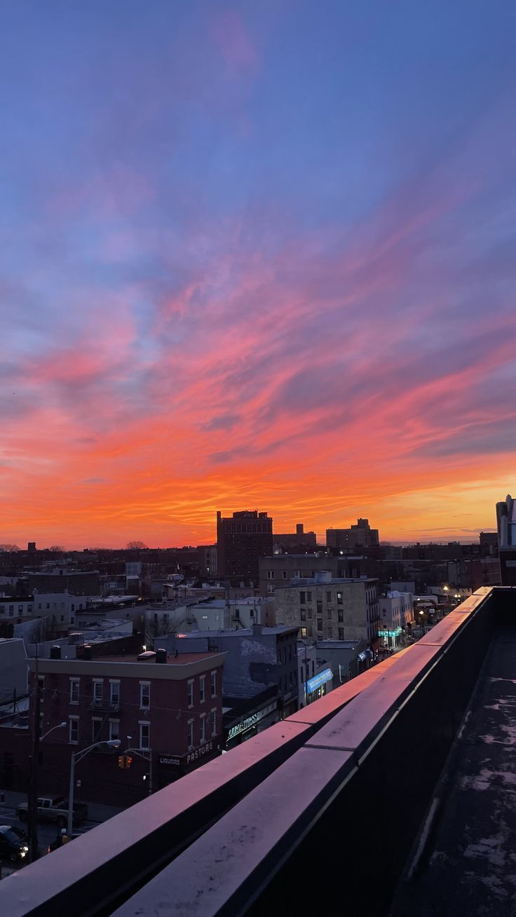 the sky is pink and orange as the sun sets in the distance over city buildings