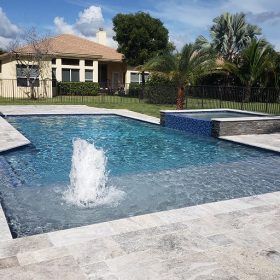 a large pool with a fountain in the middle of it and a house in the background