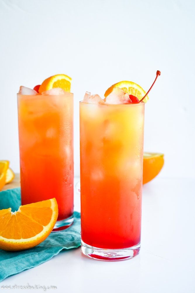 two tall glasses filled with orange juice and garnished with an orange slice on the rim