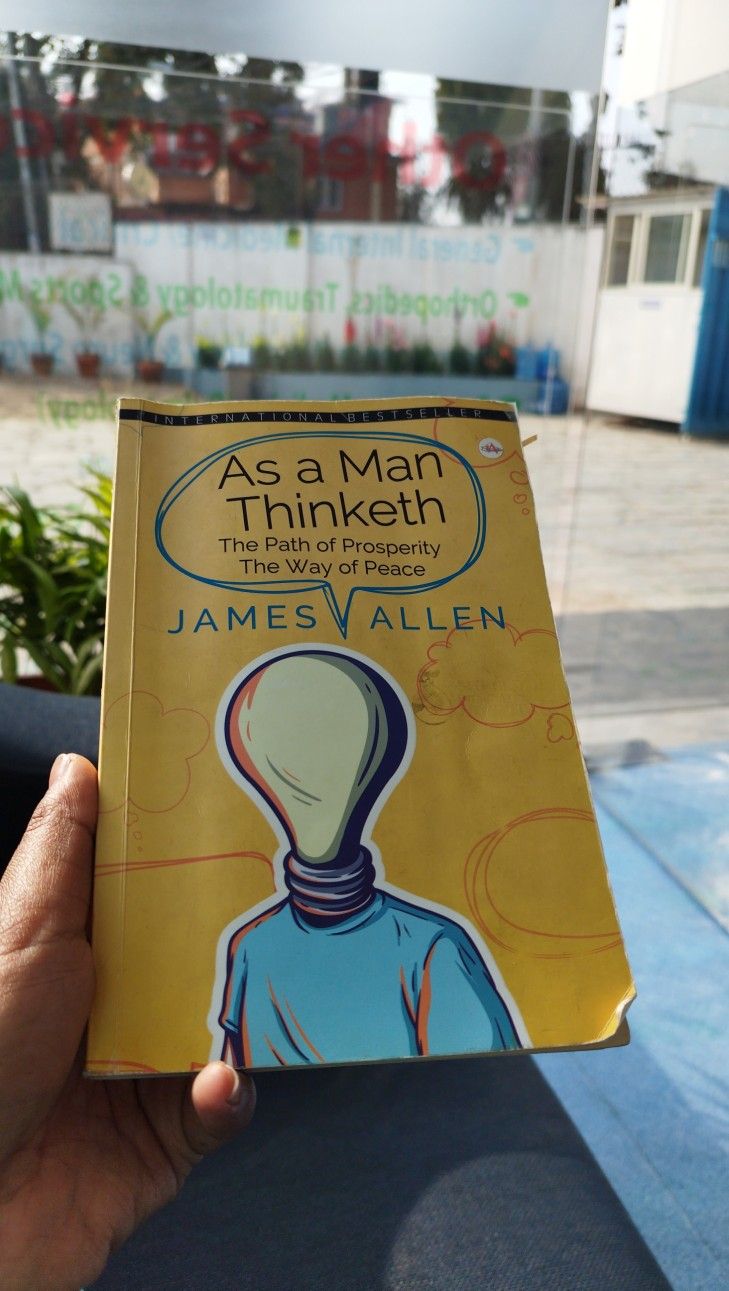 a person holding up a book in front of a blue and white building with the title as a man thinketh