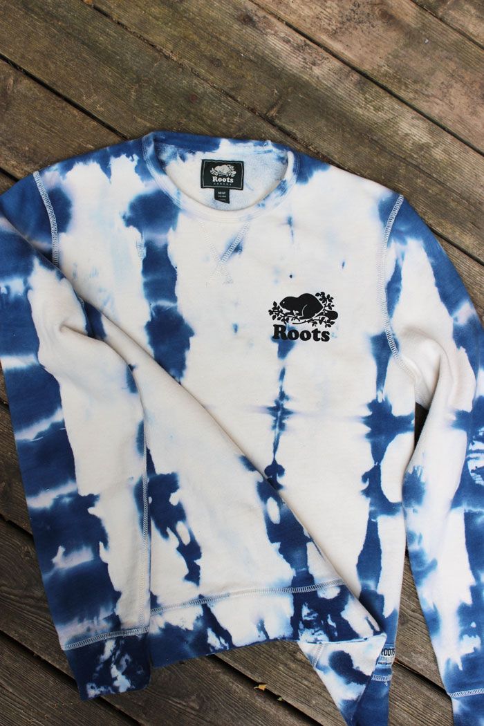 a blue and white tie - dyed sweatshirt sitting on top of a wooden floor with the words roots printed on it