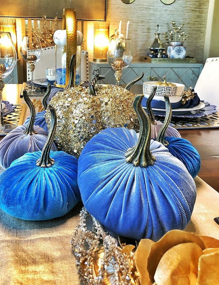 three blue pumpkins sitting on top of a table next to other decorative items and candles