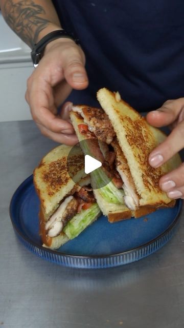 a person is holding a sandwich on a blue plate