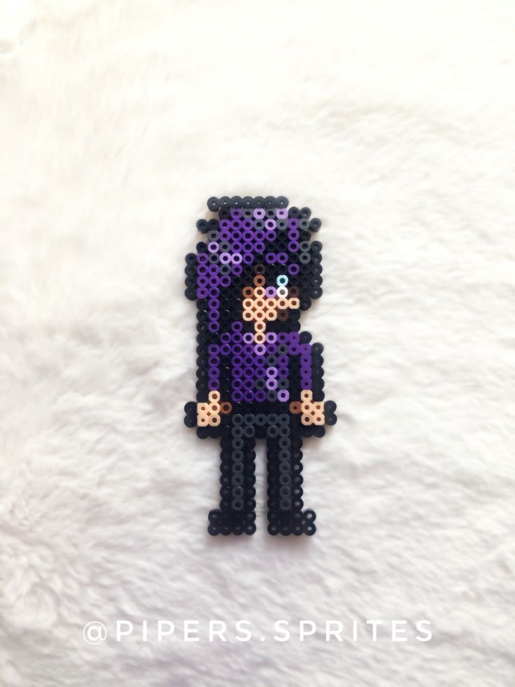 a purple pixel art piece is laying on a white surface and it looks like he's holding something in his hands