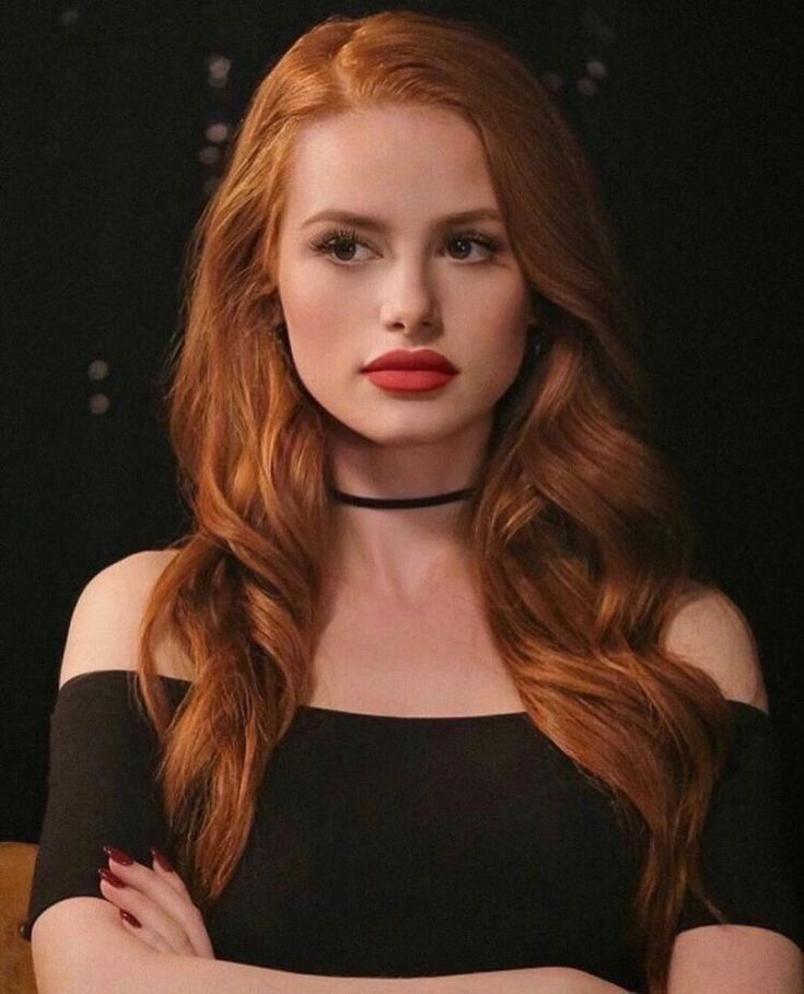 a woman with red hair wearing a choker and posing for a photo in front of a black background