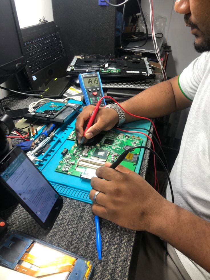 a man is working on an electronic device with wires and other electronics in front of him