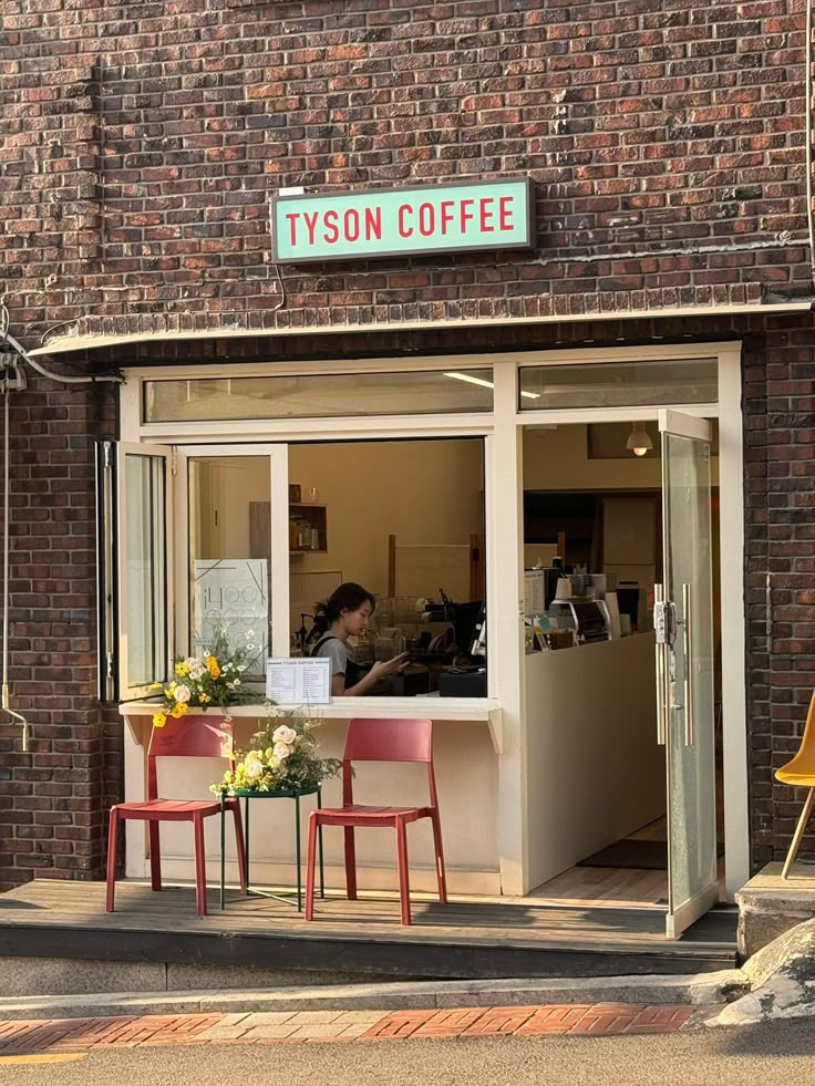 two red chairs sitting in front of a brick building with a sign that reads tyson coffee