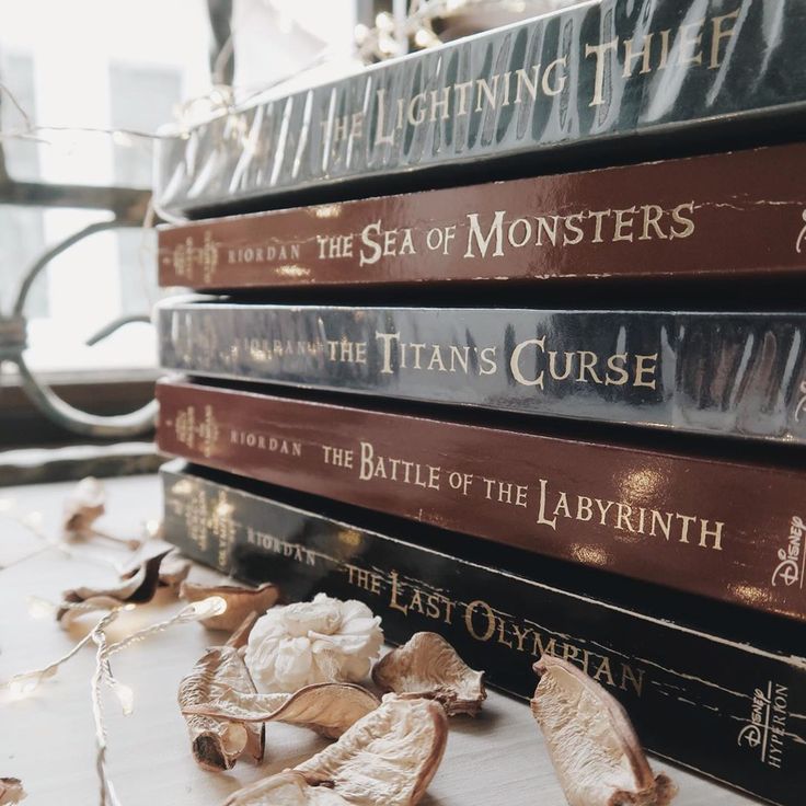 a stack of books sitting next to each other on top of a white table covered in leaves