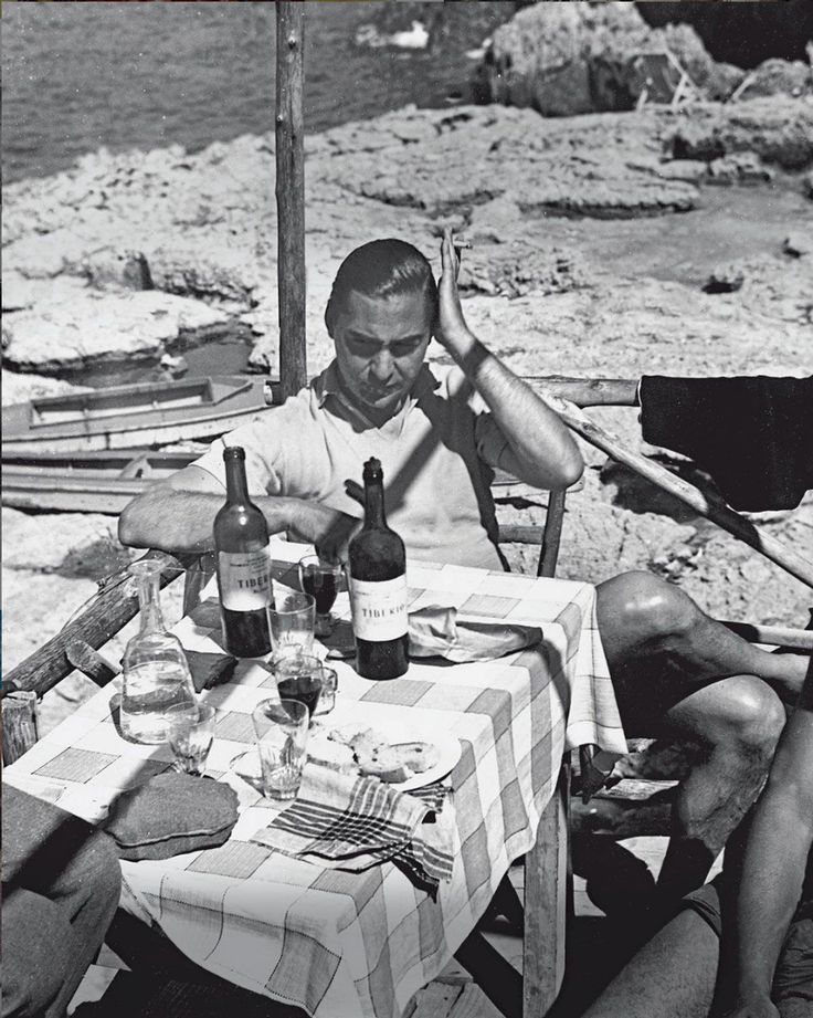 two men sitting at a table with bottles of wine