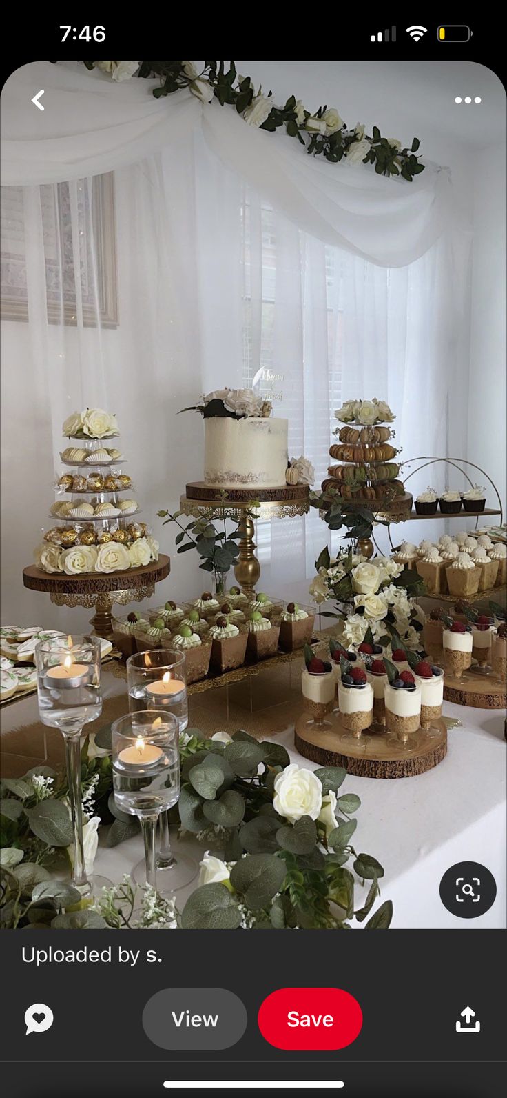 a table topped with lots of cupcakes covered in frosting and greenery