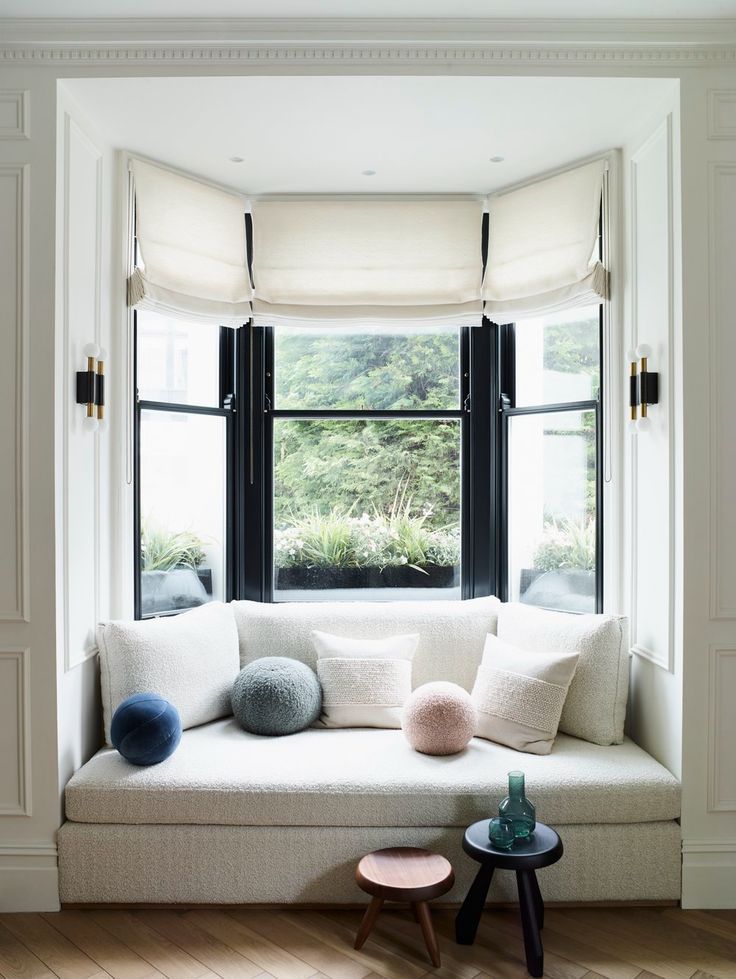 a white couch sitting under a window next to a table with two pom poms on it