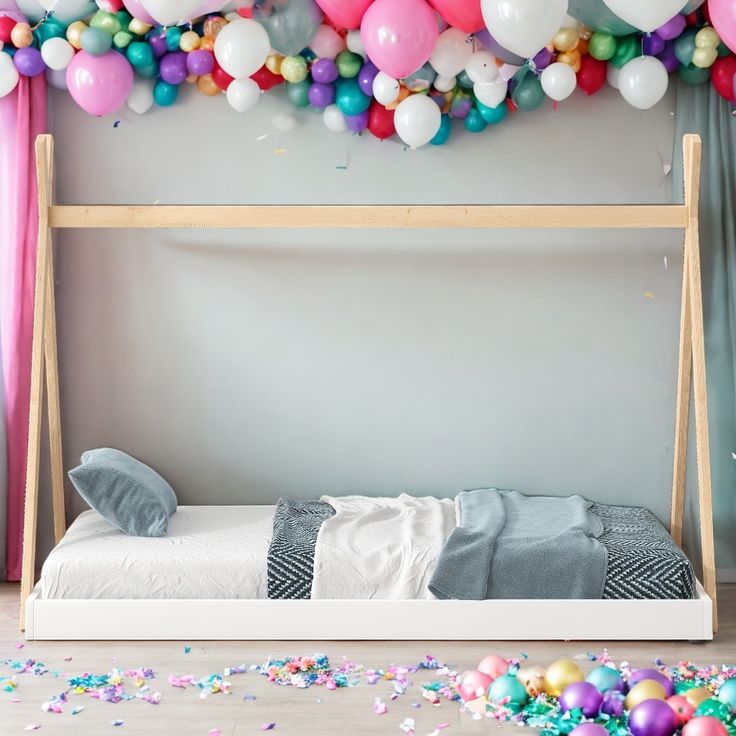 a bed with balloons and confetti on the wall next to it in a bedroom