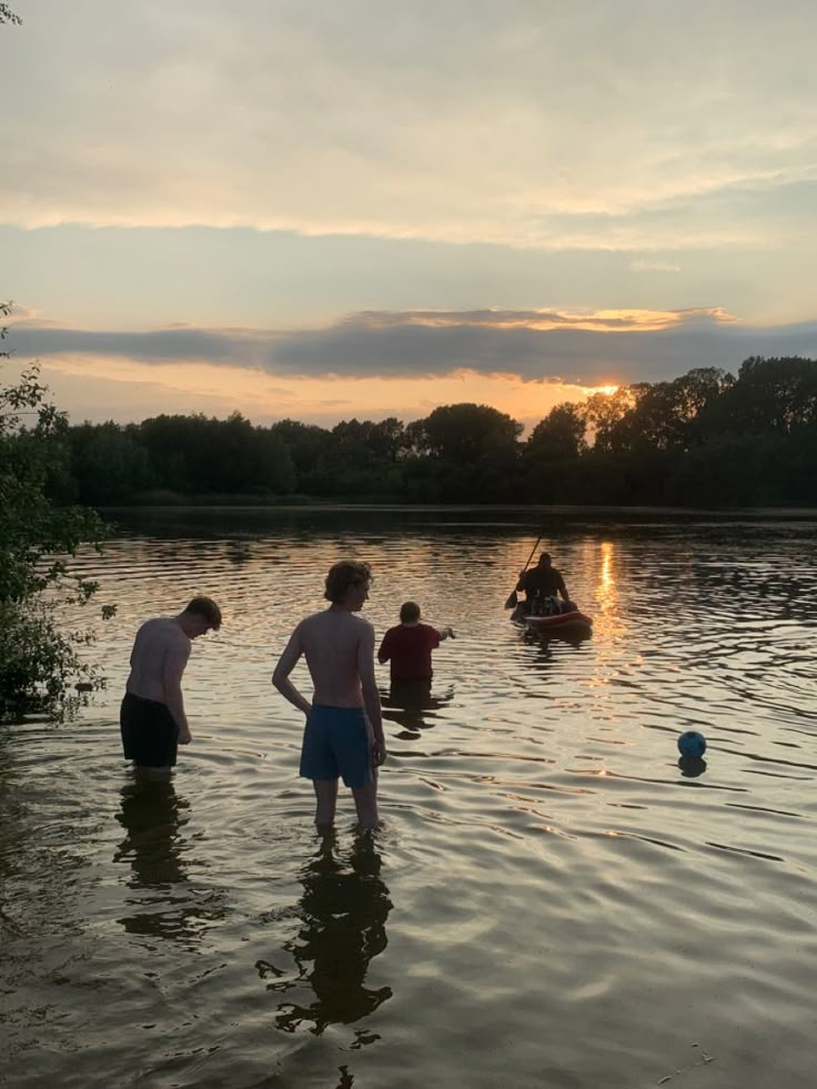 people are standing in the water at sunset