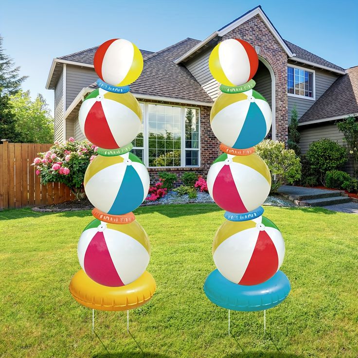 three inflatable beach balls are stacked on top of each other near a house