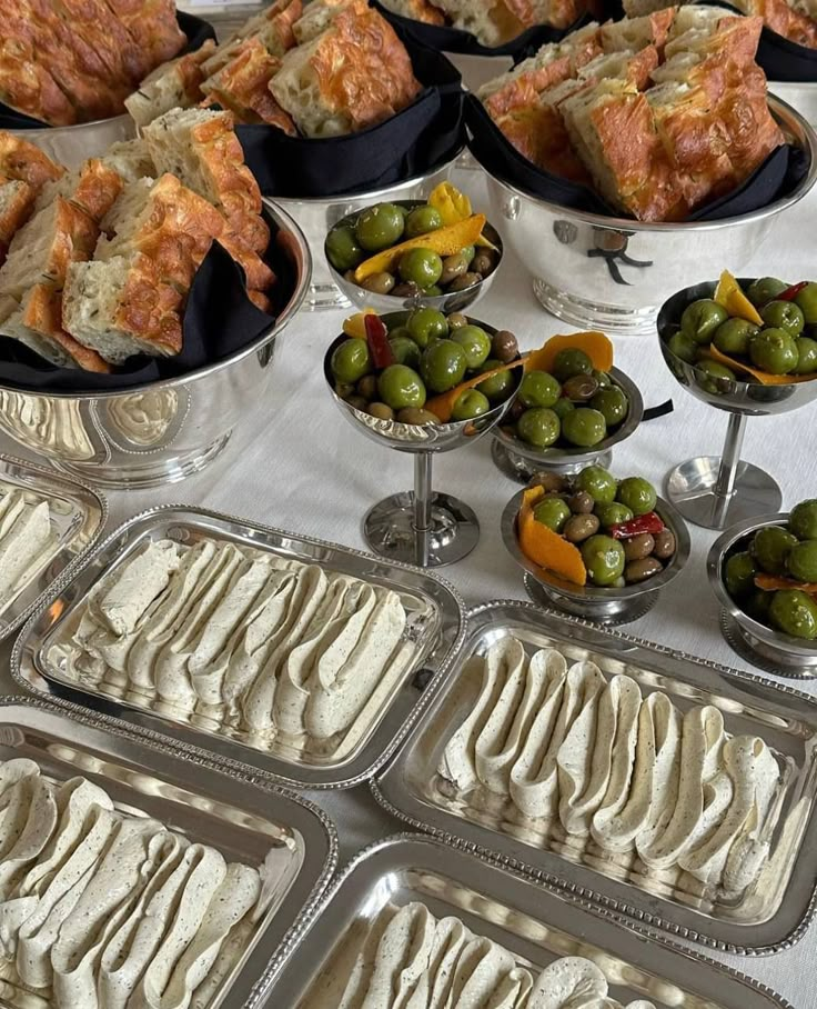 an assortment of desserts are displayed on trays and in bowls, along with olives