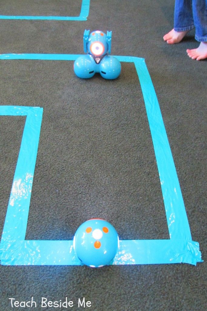 two children are playing with toys on the floor in an indoor play area that is made out of blue tape