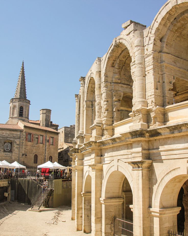 an old stone building with arches and people walking around the courtyard area in front of it