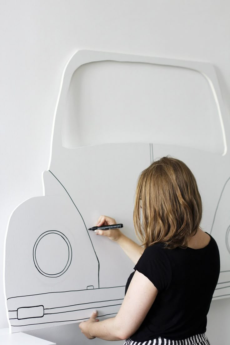 a woman writing on a white board with a vw bug design