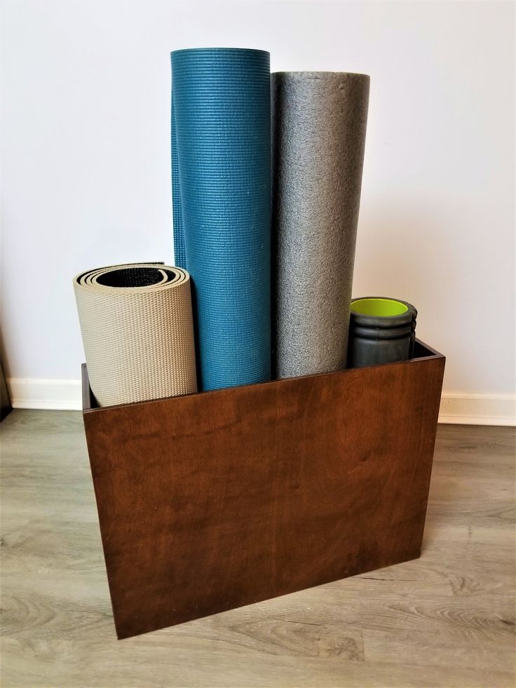 there are many different types of yoga mats in this wooden holder on the floor,