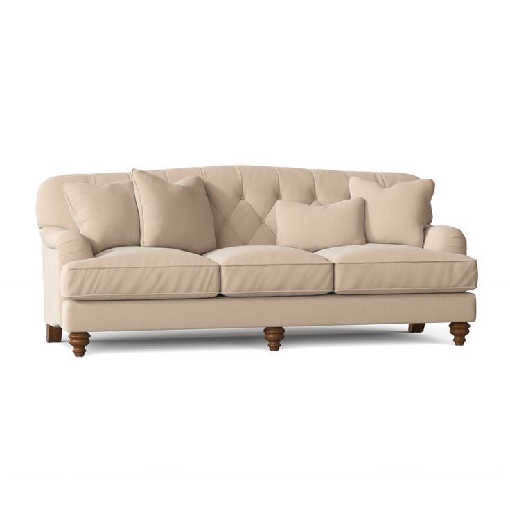 a beige couch with several pillows on the armrests and one pillow sitting on top of it