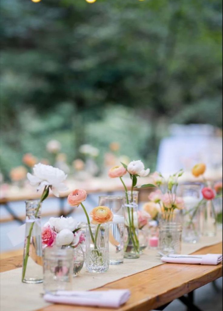 a long table with vases and flowers on it