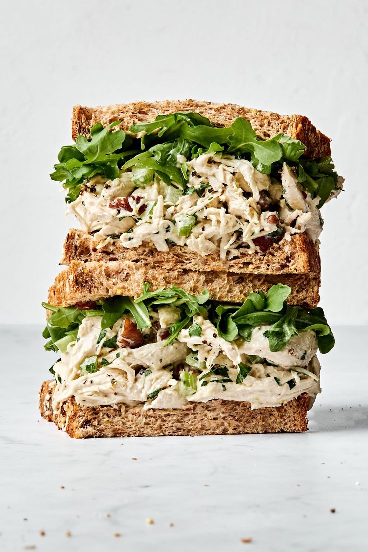 two sandwiches stacked on top of each other with lettuce and chicken in the middle