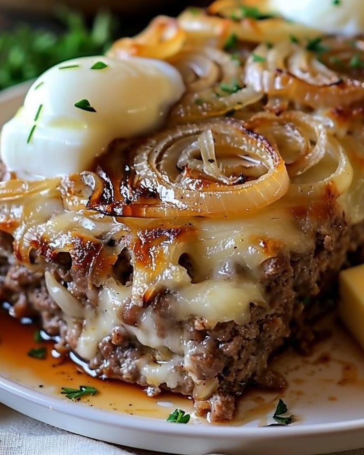 a piece of meatloaf with cheese and onions on a plate