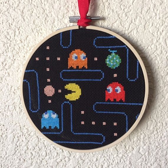 a cross stitch ornament hanging on a wall with space shuttles and planets