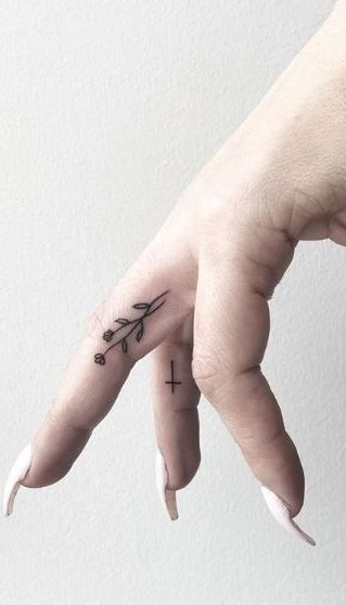 a person's hand with a small cross tattoo on the middle finger and an arrow in the middle