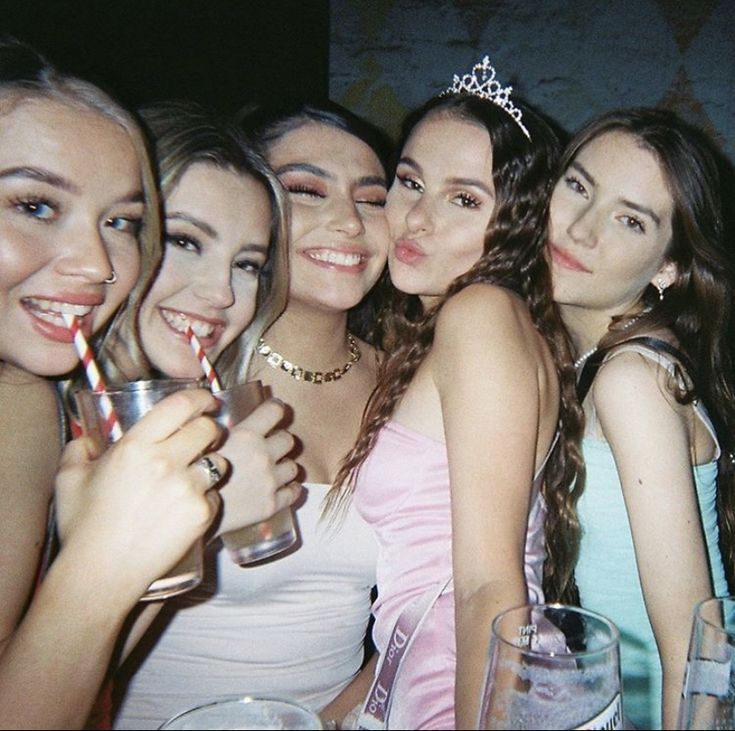 a group of women posing for a photo with drinks in their hands and wearing tiaras