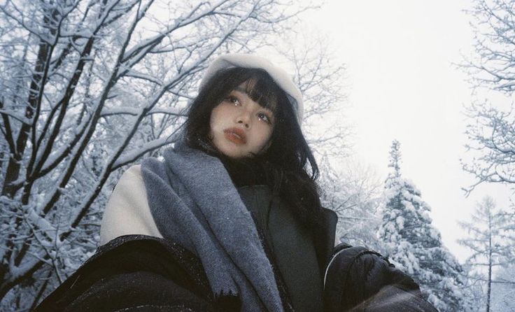 a woman standing in the snow wearing a scarf