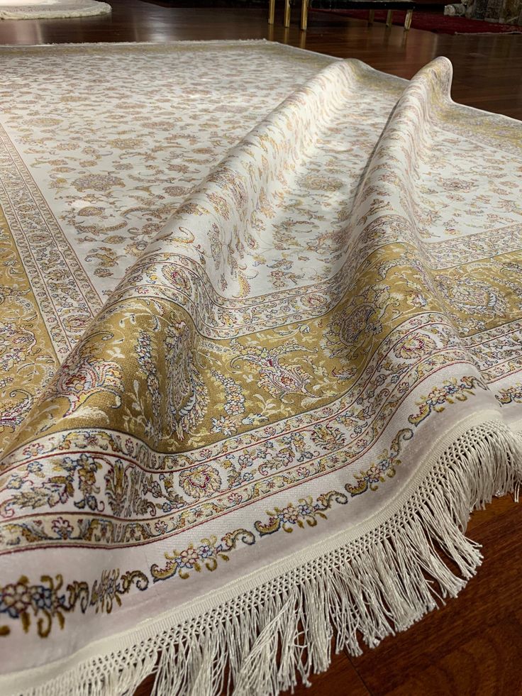 a large white and gold rug with fringes on it