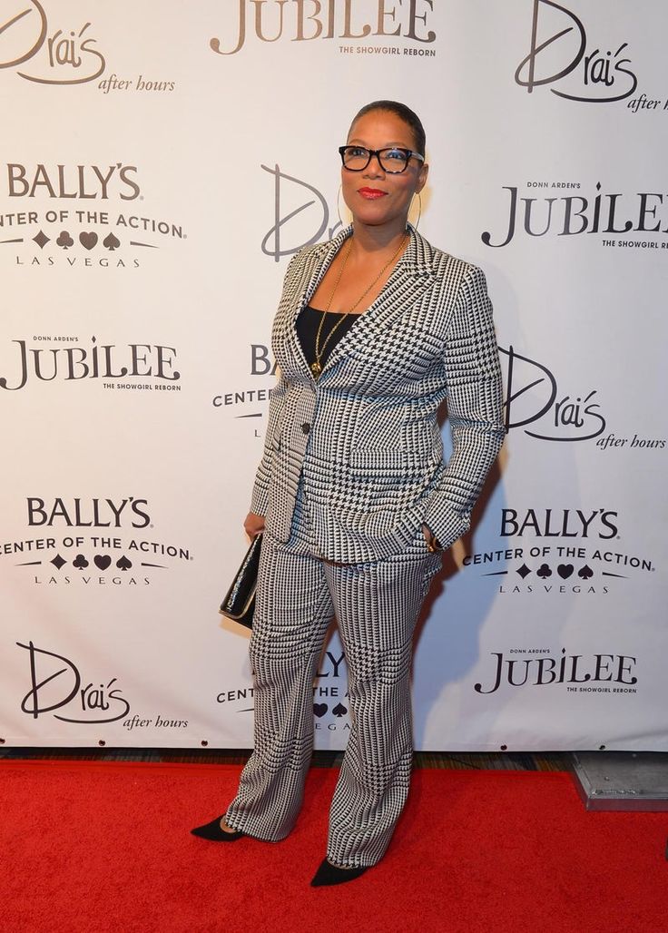 a woman standing on a red carpet wearing a suit