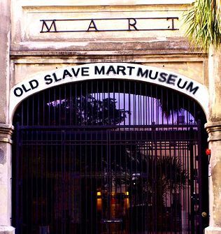 the entrance to an old slave museum with iron gates and palm trees in the background