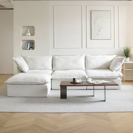 a white couch sitting on top of a wooden floor in a living room next to a coffee table