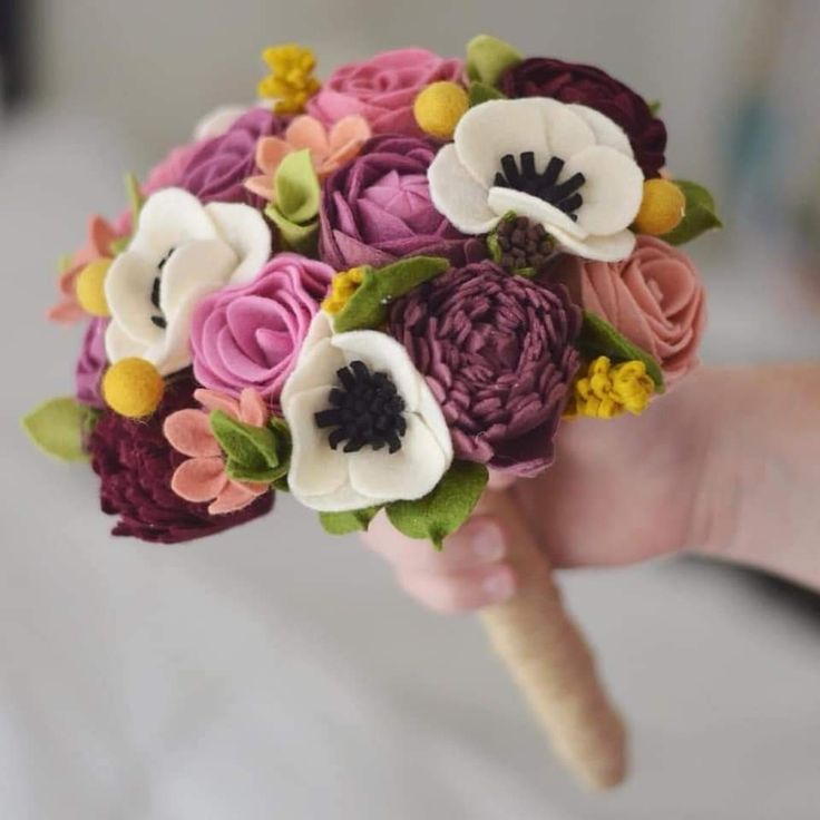 a bridal bouquet with flowers is being held in someone's hand