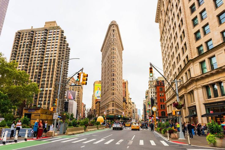 a city street with tall buildings and people walking on the sidewalk in front of it