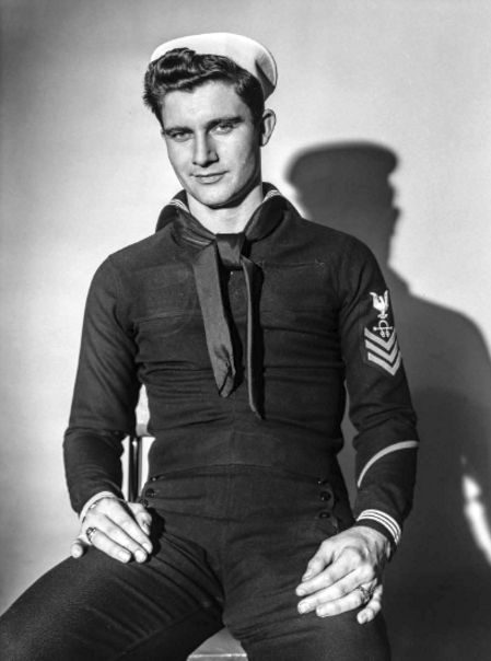 an old photo of a man in uniform sitting on a chair with his arms crossed