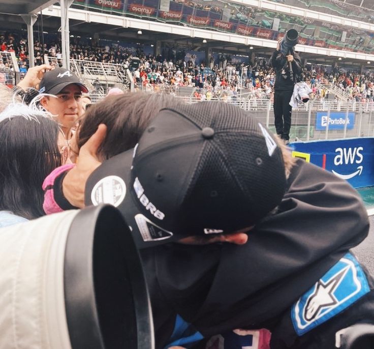 a man in a baseball cap is surrounded by people at a sporting event and taking pictures