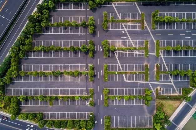 an aerial view of a parking lot with many cars parked in it and trees lining the sides