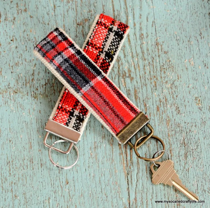 a red and black checkered keychain on a wooden surface with a metal hook