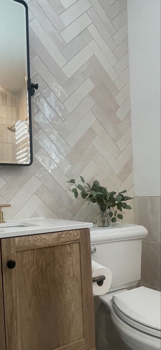 a white toilet sitting next to a wooden cabinet in a bathroom under a large mirror