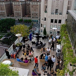 a group of people sitting on top of a building next to trees and buildings in the background