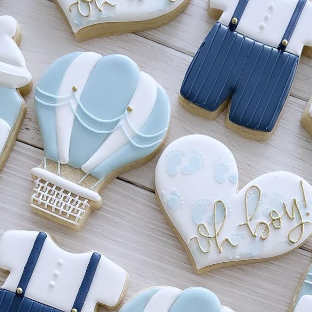 cookies decorated with blue and white icing are arranged on a wooden surface, including an air balloon