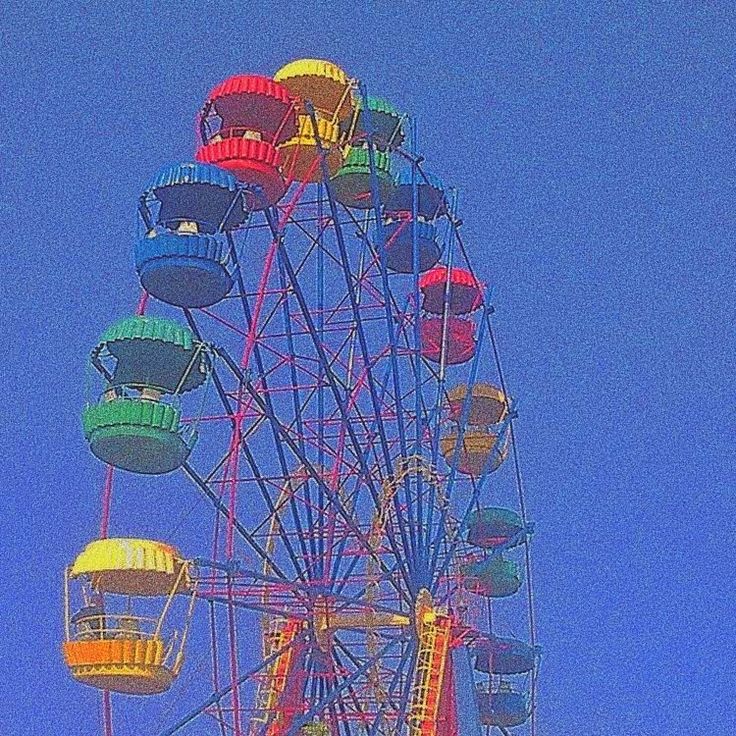 the ferris wheel is brightly colored against a blue sky